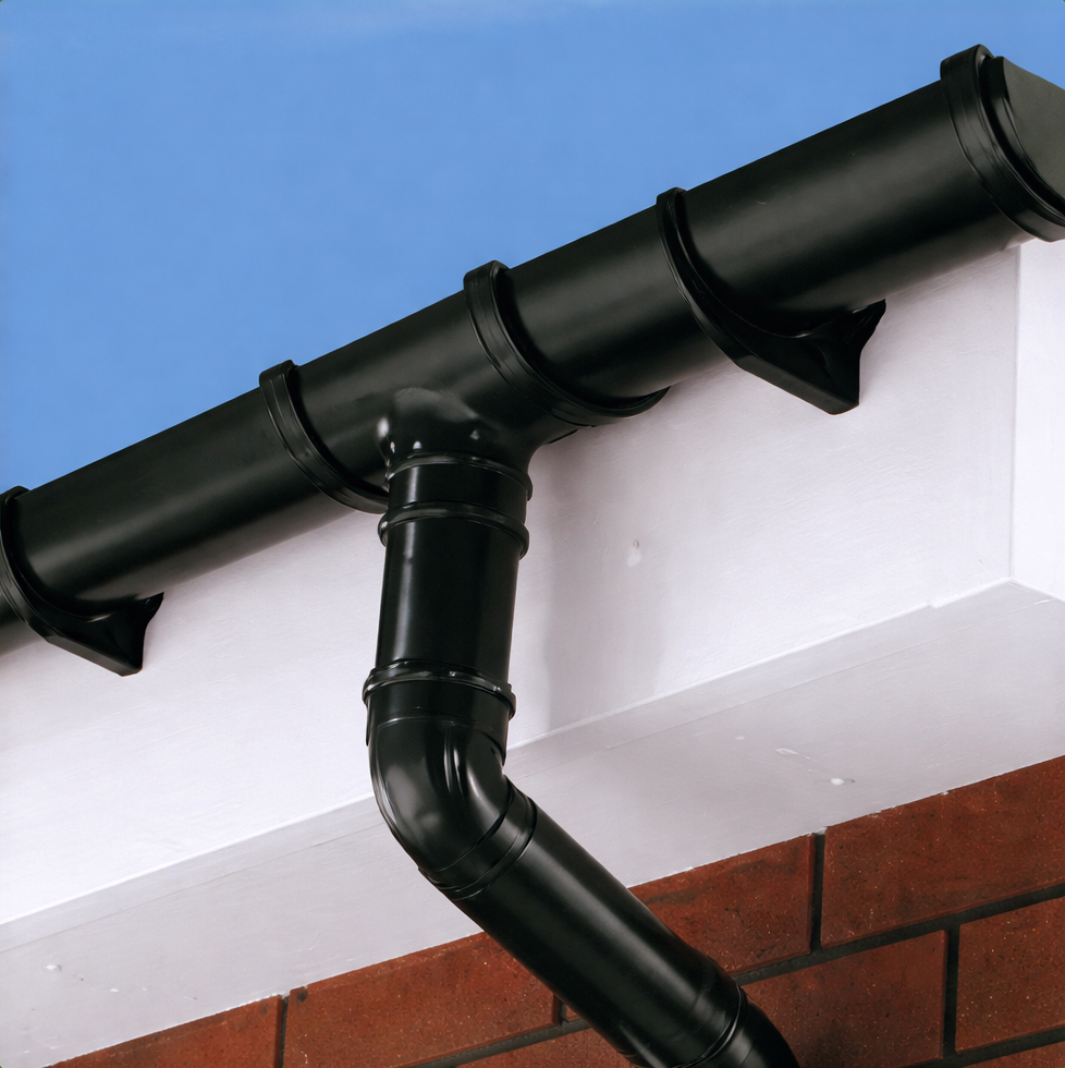 Close up shot of new black gutter and downpipe and brilliant white fascia and soffits