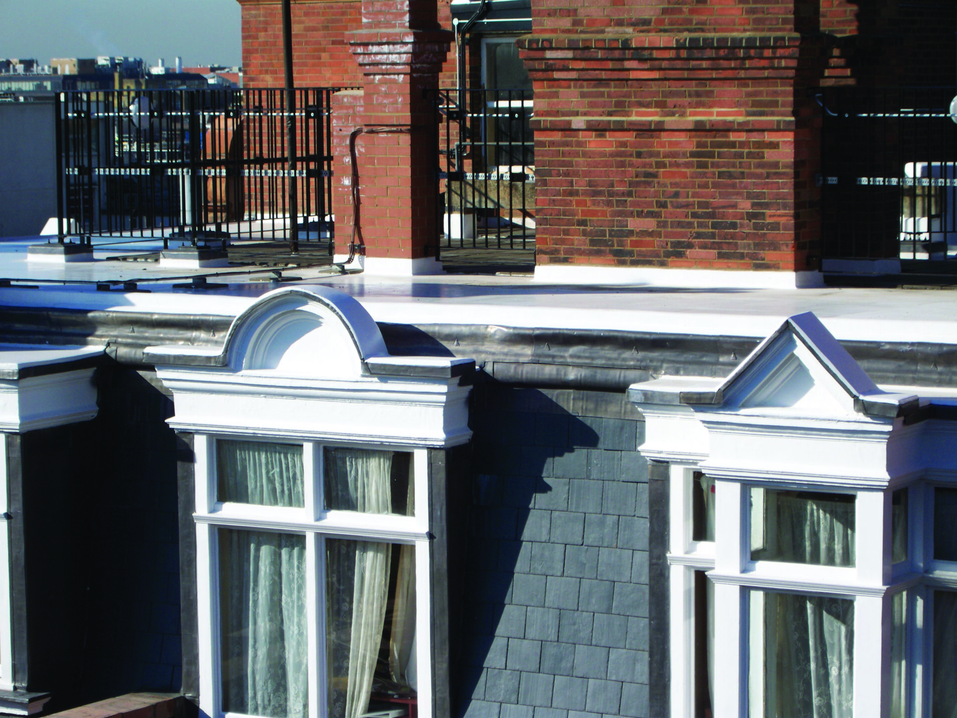 Flat roof with windows and slate cladding in foreground.